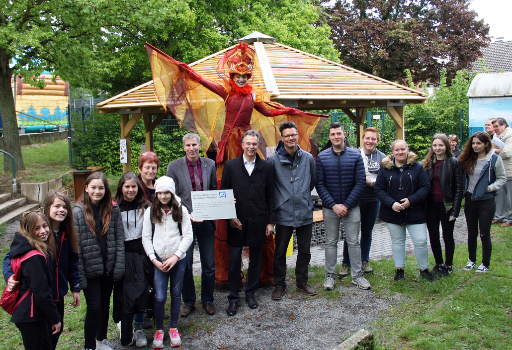 Feierliche Eröffnung des neuen Pausenhof-Pavillons am 4. Mai. Schulleiter Stephan Gericke (mit Tafel), Heike Schlößer (stellv. Schulleiterin, 5. v. l.), Ernst Uhing (Präsident Architektenkammer NRW, 8. v. l.), Projekt-Landschaftsarchitekt Andreas Hermanns (9. v. l.) und Schülervertretungssprecher Phil van der Meeren (10. v. l) mit Schülerinnen und Schülern der Willy-Brandt-Gesamtschule Übach-Palenberg. – Foto: Christof Rose / Architektenkammer NRW