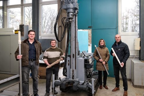 Philipp Dietrich von der Firma Otto Quast, Johannes Kuhlmann vom Lehrstuhl für Geotechnik, Lehrstuhlinhaberin Prof. Dr.-Ing. Kerstin Lesny und Andreas Reinfeld von Jacbo Pfahlgründungen (v.l.n.r.) mit den Bohrwerkzeugen an der Versuchsgrube.